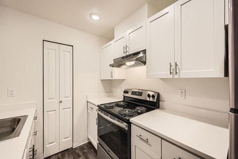 A kitchen with white cabinets and appliances.